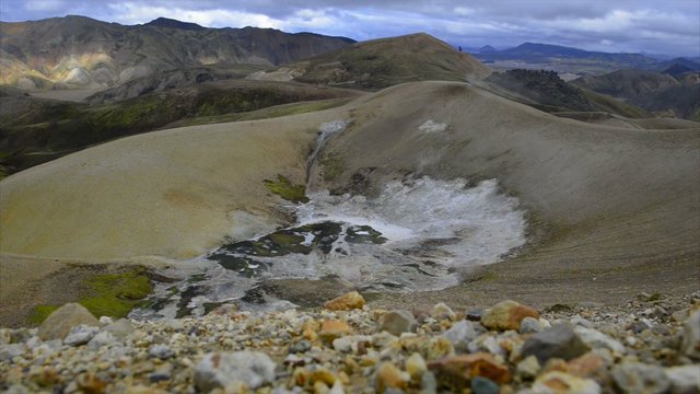 Steam rising up from hot springs in the earth in the colorful mountains of the Landmannalaugar area in Iceland.