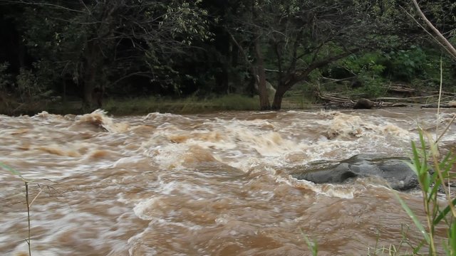 A wide angle view showing a fast moving and swollen river after a flash flood