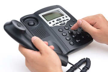 man dialing a black telephone on a white background