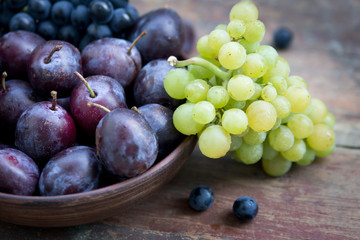 Fototapeta premium Plums and grapes on the wooden table