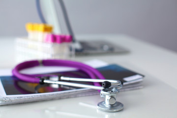 A medical stethoscope near a laptop on a wooden table, on white