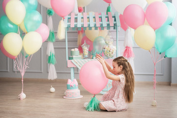 Little girl sits in a studio decorated colorful baloons