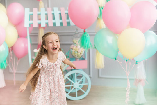 Little girl laughs in a studio decorated many balloons