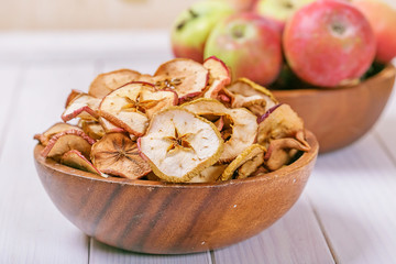 Dried and fresh apples in a bowls on a wooden background
