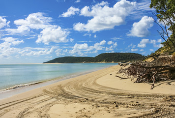 Tranquil coast line with four wheel drive tracks on white sandy beach. Looking towards Double Island Point, Queensland, Australia.