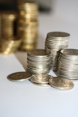 Stacks of silver five cent coins and gold coins in background.