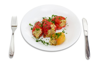 Stuffed bell peppers on a white dish, fork and knife