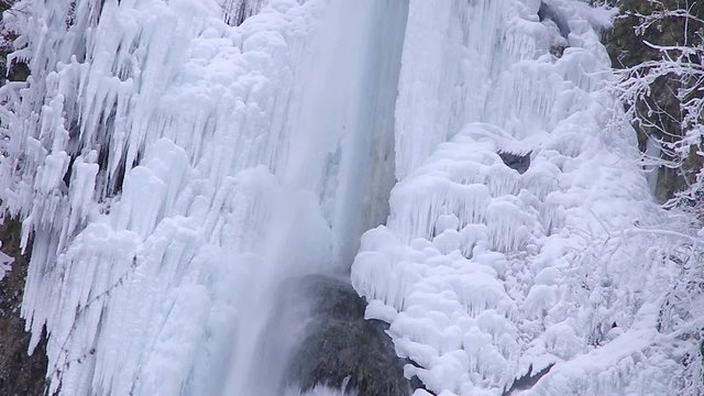Gefrorener Wasserfall - Wunderschöner eingefrorener Wasserfall im Winter mit großen Eiszapfen und etwas Wasser, dass hinab stürzt.