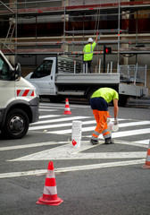 Paint agents repaint lane markings on the street. He poured white paint on the floor