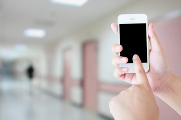 hand holding smartphone with hospital interior corridor backgrou