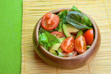 Fresh vegetable salad in wooden bowl on bamboo napkin