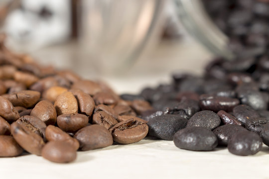 Natural roasted coffee beans and torrefacto coffee beans get out of overturned glass pots