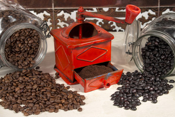 Traditional manual coffee grinder beside different types of coffee beans