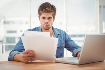 Hipster looking at documents while sitting at desk