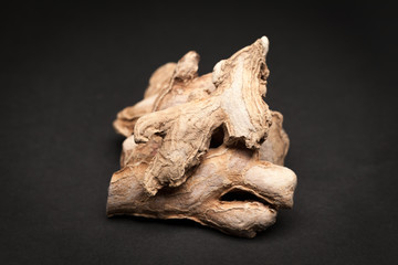 Organic Dried Ginger root or Sonth (Zingiber officinale) on dark background.