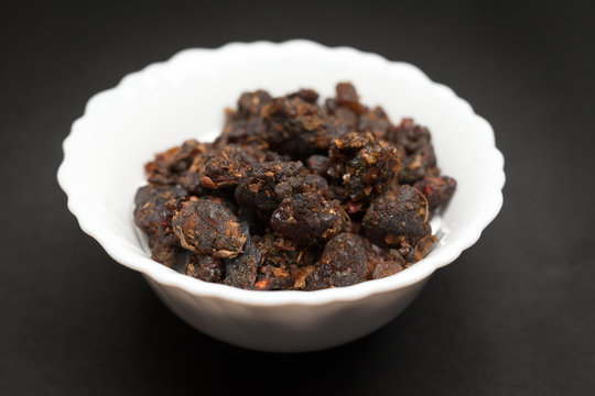 Organic Indian bdellium or Guggul resin (Commiphora wightii) in white ceramic bowl on dark background.