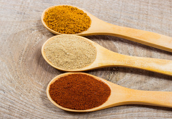 Spice powder on a wooden background. Closeup on paprika, curry and ginger.