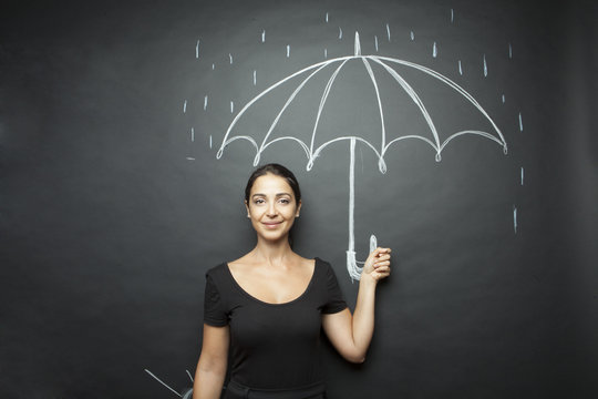 Bella ragazza regge un ombrello disegnato su lavagna