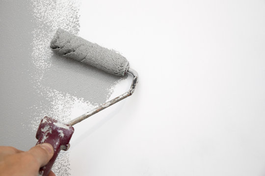 Gray Color Painting Wall With Roller In Hand