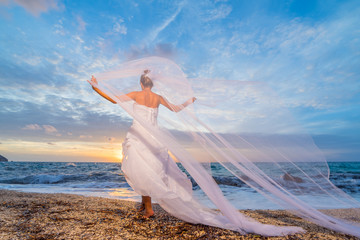 Fototapeta na wymiar YOung bride by the sea at sunset