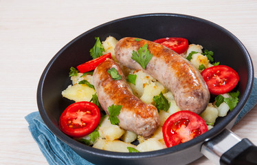 Potatoes with sausages in a frying pan
