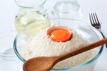 Fototapeta na wymiar white flour with egg and wooden spoon