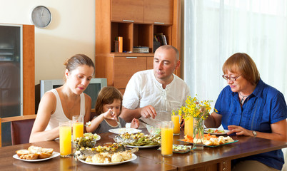 Obraz na płótnie Canvas Happy family eating fish with vegatables at home