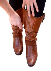 Woman holds her brown leather boots while zipping them up