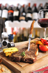 T-Bone steak barbecue with fried potato and red wine on wood table