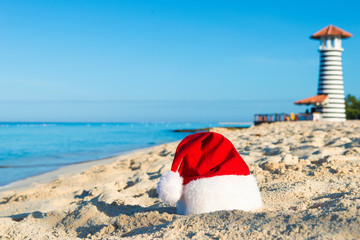 Happy  New Year holidays at Sea. Santa hat on sandy beach - christmas holiday concept