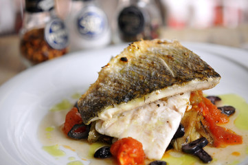 Grilled fish and garnitures in plate and white wine on wooden table
