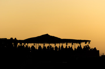 People on a beach party event in sunset. Dancing and partying.