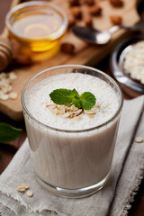 Healthy breakfast of banana smoothie or milkshake with oats and honey decorated mint leaves on rustic surface
