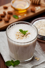 Healthy breakfast of banana smoothie or milkshake with oats and honey decorated mint leaves on rustic surface