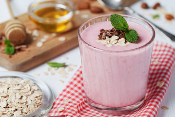 Healthy breakfast of berry smoothie or milkshake with oats and honey decorated mint leaves and grated chocolate on linen napkin