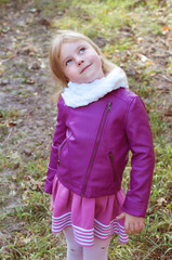 Cute little blond girl in a white scarf looking like a daredevil