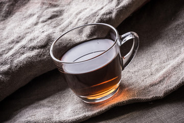 Green tea in transparent glass on linen fabric.