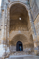 Fototapeta na wymiar Mujer entrando a la catedral de Palencia por una de sus puertas de entrada principales