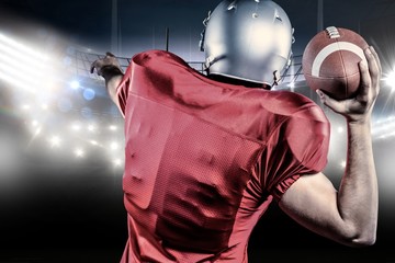 Fototapeta na wymiar Rear view of American football player throwing ball against american football arena