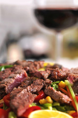 Seasonal salad with beef and red wine on wooden table