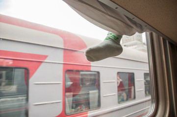 Fototapeta premium Childrens leg hanging from the side of the top shelf second-class train carriage