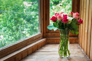 Fototapeta na wymiar Vase with flowers standing near the window