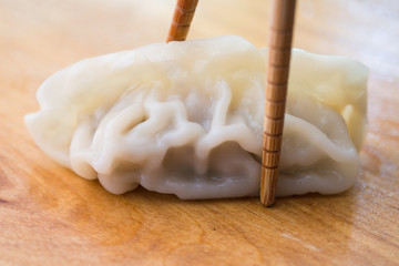 Chinese dumplings or Jiaozi with chopstick on wooden board