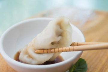 Chinese dumplings or Jiaozi with chopstick on wooden board