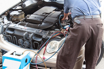 Mechanic with manometer filling gas into auto vehicle air-condit