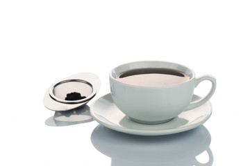 Freshly brewed hot tea in cup saucer with tea sieve