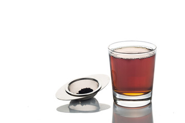 Freshly brewed hot tea in transparent glass with tea sieve