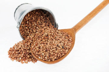 Bucket of buckwheat crumbles in the a wooden spoon