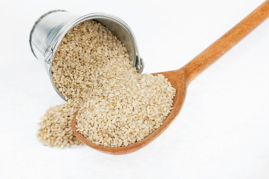 Bucket of sesame crumbles in the a wooden spoon