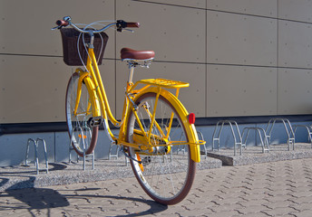 Fototapeta na wymiar Yellow bike with basket parking at bike rack on street.